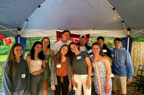 Students pose at welcome event outside under a tent