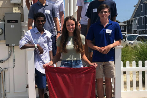 Students stand on steps holding a Lafayette banner outside at New Jersey Welcome Event