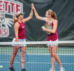 Olivia Beckman ‘25 and Maureen McCormack ‘22 are on a tennis court and are high fiving