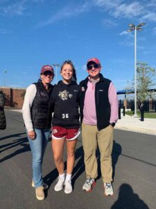 Greg and Aileen Tuorto P'23 are standing outside with their daughter, Kerry'23